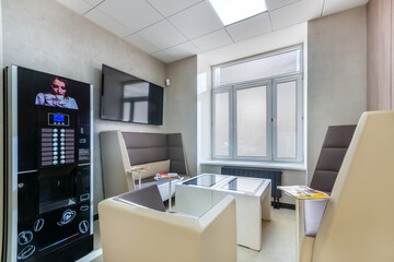 The waiting area in a modern sales office with a vending coffee machine, soft leather sofas and a coffee table.