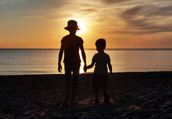 boy and girl walk along the seashore at sunset