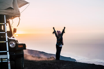 Happy joy people travel with car and tent roof in wild places enjoying the sunset on the top of a...