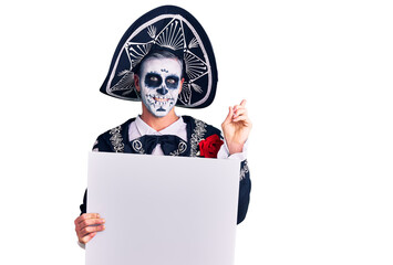 Young man wearing day of the dead costume holding blank empty banner smiling happy pointing with hand and finger to the side