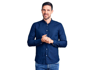 Young handsome man wearing casual shirt with hands together and crossed fingers smiling relaxed and...
