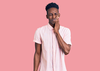 Young african american man wearing casual clothes touching mouth with hand with painful expression because of toothache or dental illness on teeth. dentist