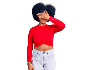 Young african american girl wearing casual clothes and glasses covering eyes with hand, looking serious and sad. sightless, hiding and rejection concept