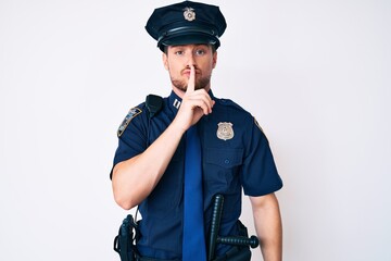 Young caucasian man wearing police uniform asking to be quiet with finger on lips. silence and secret concept.