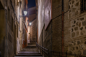 lighthouses illuminating an alley and staircase in the historic center of the city of toledo at night. Spain - obrazy, fototapety, plakaty