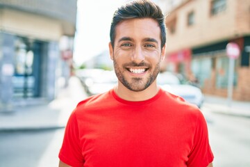 Young handsome hispanic man smiling happy. Standing with smile on face walking at town street.