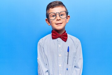 Cute blond kid wearing nerd bow tie and glasses with a happy and cool smile on face. lucky person.