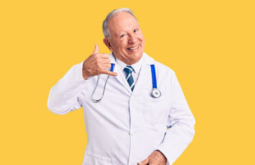 Senior handsome grey-haired man wearing doctor coat and stethoscope smiling doing phone gesture...