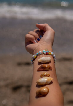 Mano cerrada con pulseras y conchas de mar.