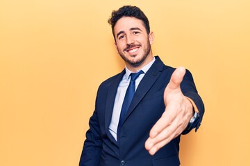 Young hispanic man wearing suit smiling friendly offering handshake as greeting and welcoming. successful business.
