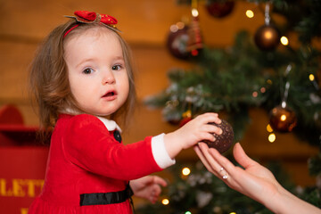 Fabulous Christmas holidays mom and daughter in red dresses decorate the Christmas tree. Cozy family holiday
