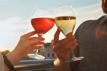 Close up cropped shot of a loving couple clinking wine glasses on sunset outdoors