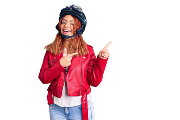 Young latin woman wearing leather jacket holding motorcycle helmet smiling and looking at the camera pointing with two hands and fingers to the side.