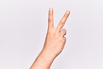 Close up of hand of young caucasian man over isolated background counting number 2 showing two fingers, gesturing victory and winner symbol