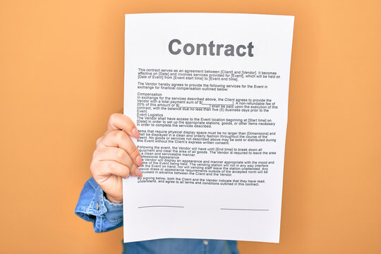 Woman holding contract document paper standing over isolated yellow background