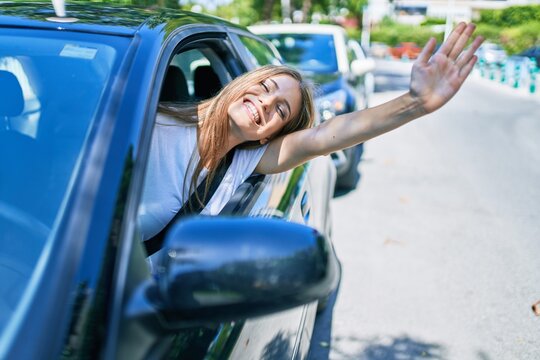 Young beautiful blonde woman smiling happy sitting at the car with hand out and cheerful expression