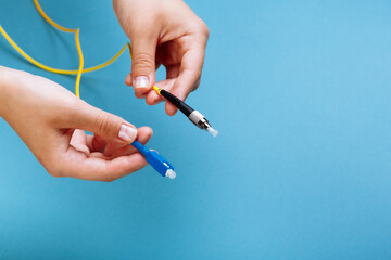 woman's hands hold SC and FC connector fiber optic patch cord single mode on blue background