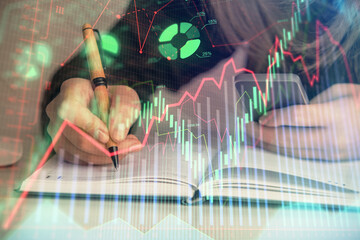 Double exposure of businesswoman hands typing on computer and forex graph hologram drawing....