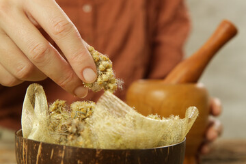 Woman preparing natural medicines with mortar and pestle. Process of making natural cosmetic or herbal infused oil.