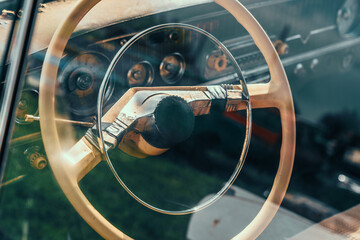 Steering wheel of old abandoned rusty car, view through glass with reflection.