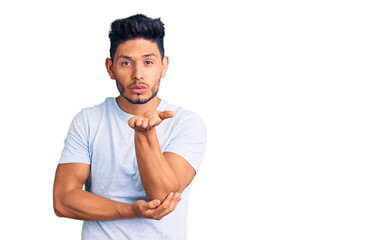 Handsome latin american young man wearing casual clothes looking at the camera blowing a kiss with hand on air being lovely and sexy. love expression.
