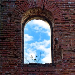 window in brick wall on blue sky with clouds