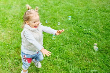 Caucasian kid happy running after soap bubbles