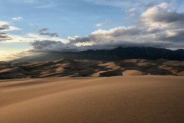Obraz na płótnie Canvas Mountain Peaks Hide in Clouds Above Sand Dunes