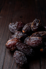 Dark dried dates on dark wood, close up, selective focus