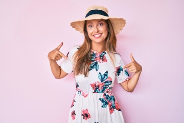 Middle age hispanic woman wearing summer hat looking confident with smile on face, pointing oneself with fingers proud and happy.