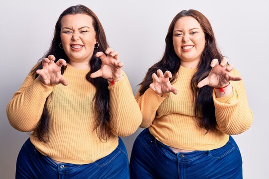 Young plus size twins wearing casual clothes smiling funny doing claw gesture as cat, aggressive and sexy expression
