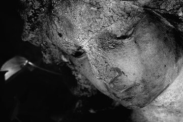 Death. Close up sad angel as symbol of pain, fear and end of life. Fragment of an ancient stone statue. Horizontal image.