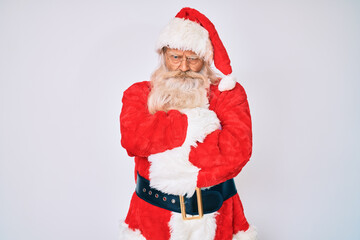 Old senior man with grey hair and long beard wearing santa claus costume with suspenders skeptic and nervous, disapproving expression on face with crossed arms. negative person.