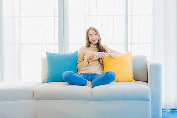 Fototapeta premium Portrait beautiful young asian woman with coffee cup on sofa decoration
