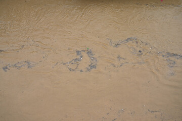 River canal in a big city. Sewage after rain carries garbage along the river.