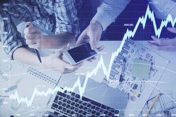 Double exposure of forex graph drawing and man and woman working together holding and using a mobile device. Trade concept.