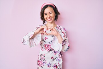 Young beautiful woman wearing casual clothes and diadem smiling in love showing heart symbol and shape with hands. romantic concept.