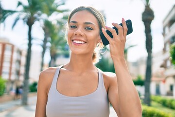Young cauciasian fitness woman wearing sport clothes training outdoors listening to voice message on the phone