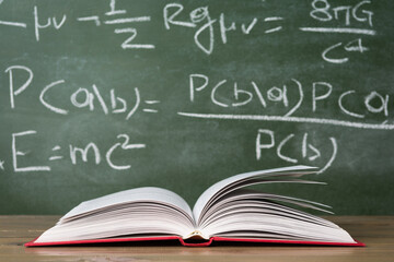 Open book against green chalkboard, close up