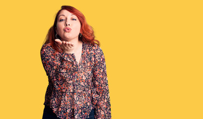 Young beautiful redhead woman wearing casual t-shirt looking at the camera blowing a kiss with hand on air being lovely and sexy. love expression.