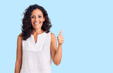 Middle age beautiful woman wearing casual sleeveless t shirt smiling happy and positive, thumb up...