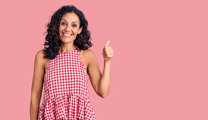 Middle age beautiful woman wearing casual sleeveless t shirt smiling happy and positive, thumb up doing excellent and approval sign