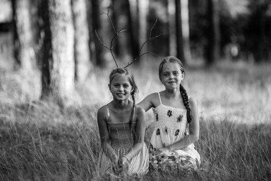 Two ten-year-old girls pose for a photo in the park. Black and white photo.