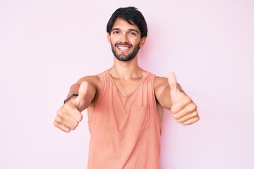 Fototapeta premium Handsome hispanic man wearing casual clothes approving doing positive gesture with hand, thumbs up smiling and happy for success. winner gesture.