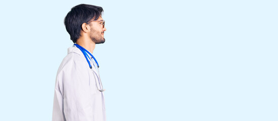 Handsome hispanic man wearing doctor uniform and stethoscope looking to side, relax profile pose...