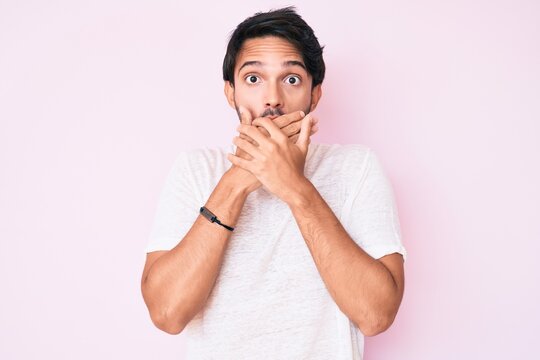 Handsome hispanic man wearing casual white tshirt shocked covering mouth with hands for mistake. secret concept.