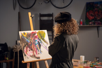 An artist in the process of drawing an abstract picture. Waiting for inspiration in the workshop