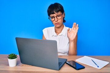 Beautiful brunettte woman working at the office doing video call skeptic and nervous, frowning...