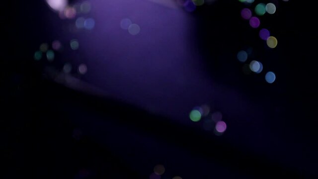 Close up animation autofocus shot of soap bubbles moving flying in air chaotically on neon violet blue dark background