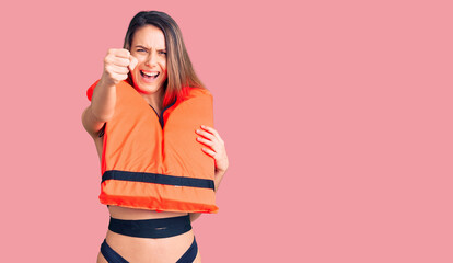 Young beautiful girl wearing life jacket annoyed and frustrated shouting with anger, yelling crazy...